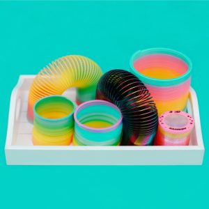 An image of a slinky collection in a white box against a turquoise backdrop.