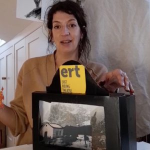 Our in-house artist Emma Garness smiling behind a model of a theatre stage made from a shoebox.